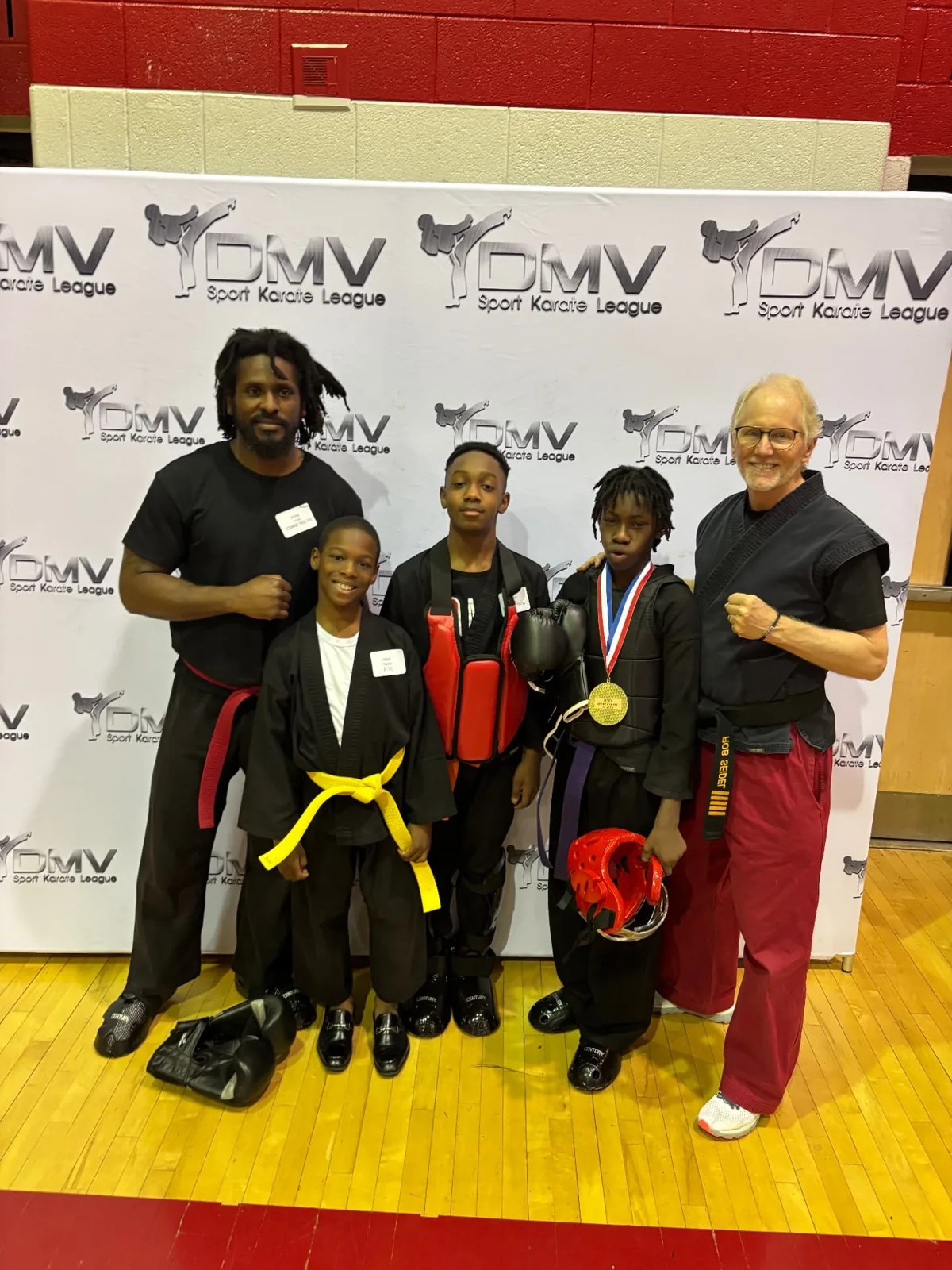 Three young martial artists with two adults at an event