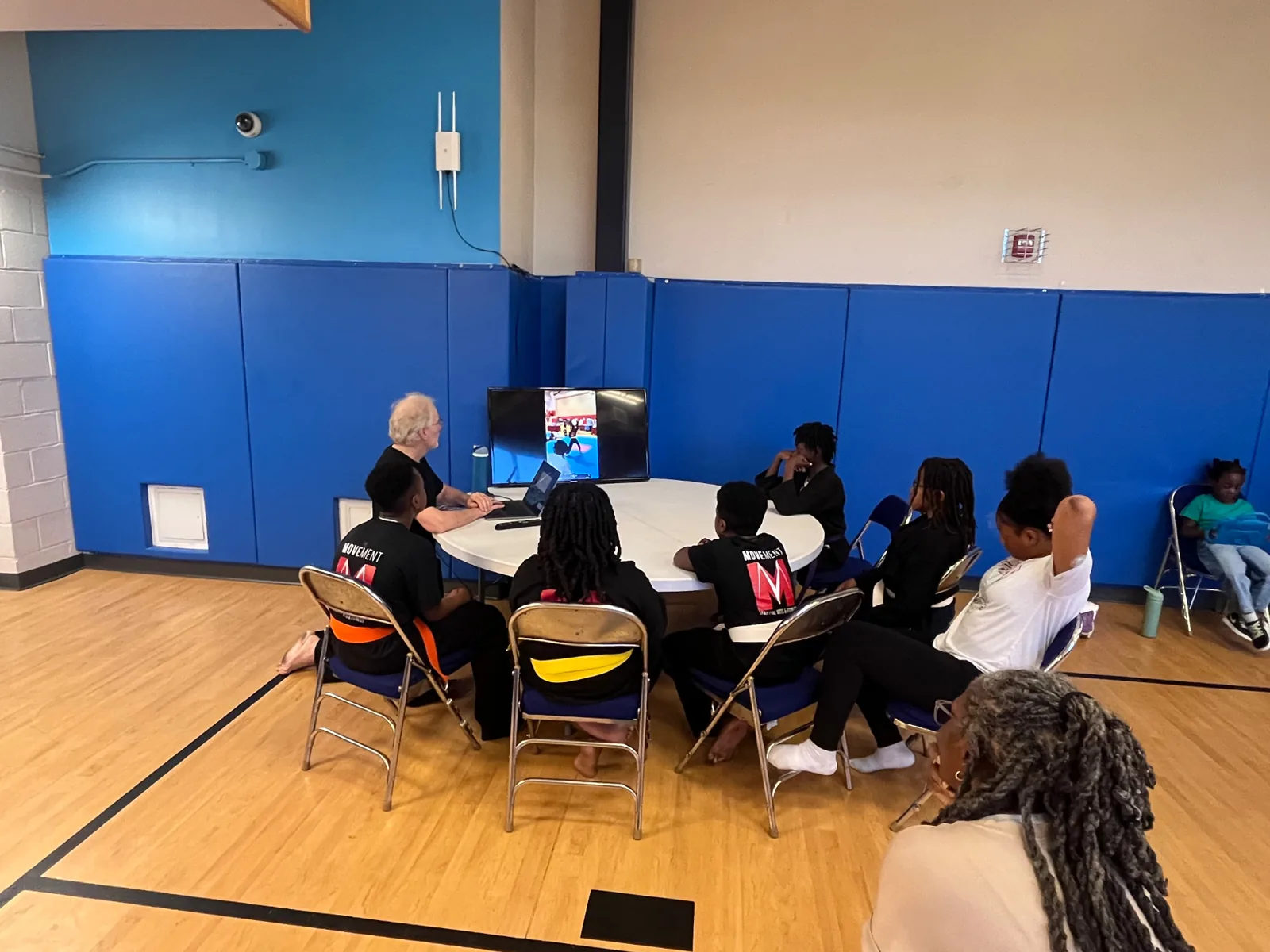 A small group seated around a table in a gym